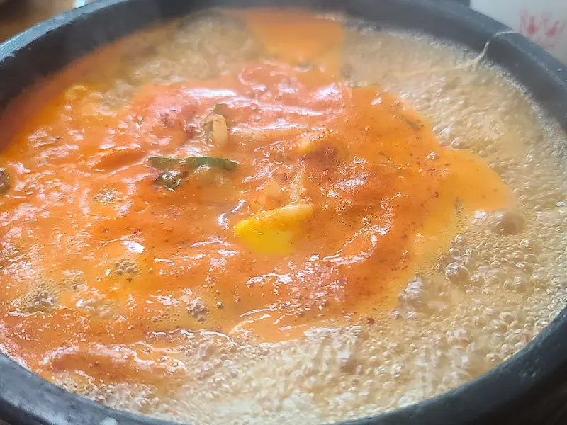 김치 콩나물 국밥이 뚝배기에 담겨 보글보글 끓고 있다.