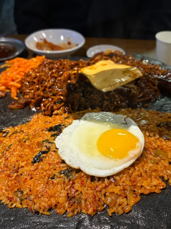 돌판 위에 짜파게티와 볶음밥이 놓여 있는 모습