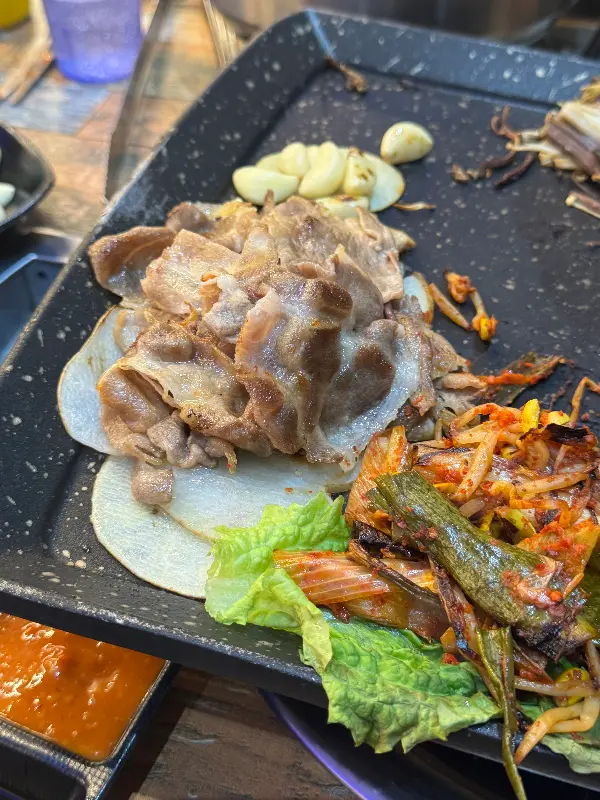 잘 구워진 대패 삼겹살과 곁들임 야채, 소스가 담긴 접시