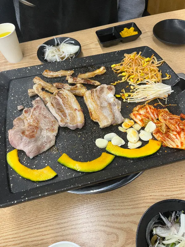 깔끔하게 정돈된 불판 위의 고기와 밑반찬