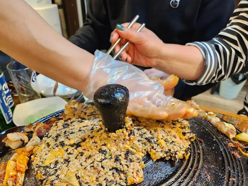 솥뚜껑 위에 볶음밥이 맛있게 볶아져 있는 모습