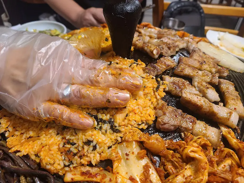 위생 장갑을 끼고 볶음밥을 솥뚜껑에 누르는 모습