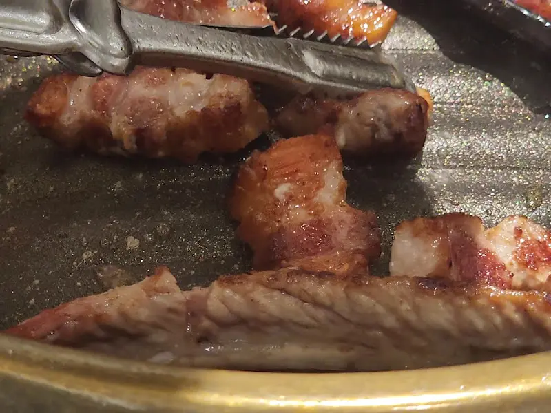 잘 구워진 삼겹살을 집게로 들어올리는 모습