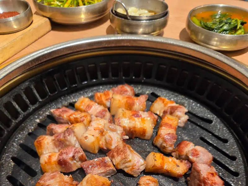 잘 익은 삼겹살과 함께 다양한 반찬들이 놓여진 테이블