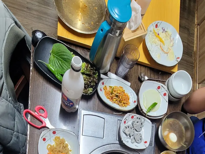 테이블에 놓여진 쌈 채소, 술, 반찬 등의 모습