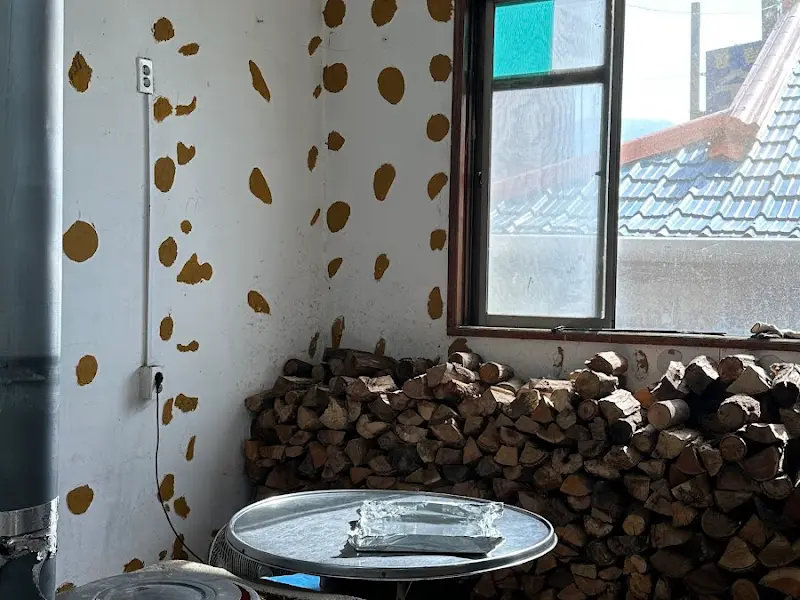 장작이 쌓여 있는 실내 풍경. 벽에는 갈색 얼룩 무늬가 그려져 있다.