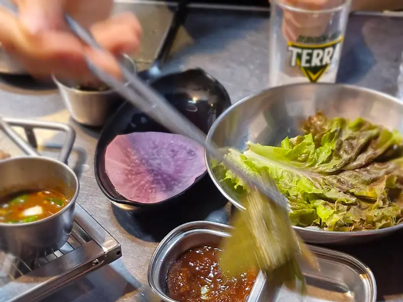 상추에 꼬들살, 쌈장, 마늘을 올려 푸짐하게 쌈을 싸 먹는 모습