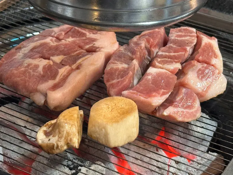 숯불 위에서 익어가는 두툼한 고기, 육즙이 좔좔 흐른다