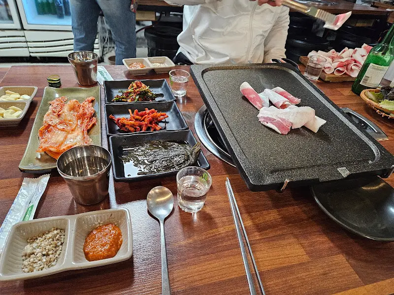 불판 위에 올려진 꽃삼겹살과 다양한 밑반찬