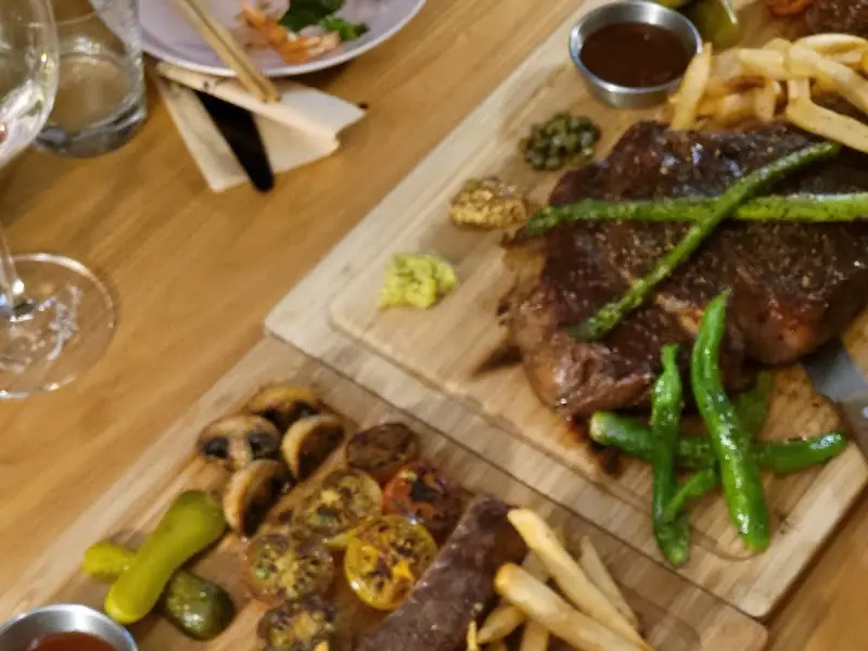 나무 도마 위에 놓인 토마호크 스테이크와 гарнир