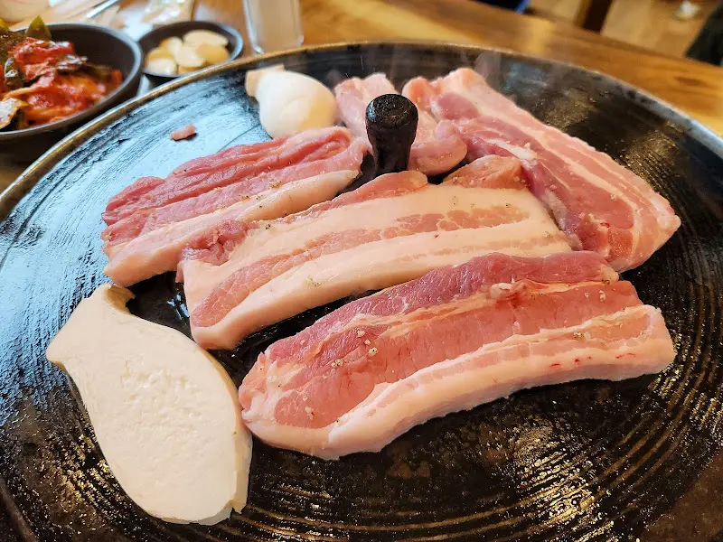 솥뚜껑 위에 올려진 삼겹살과 버섯