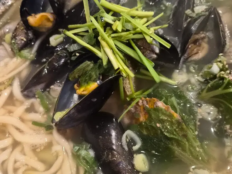 해물칼국수의 클로즈업 사진. 동죽과 미나리가 보인다.