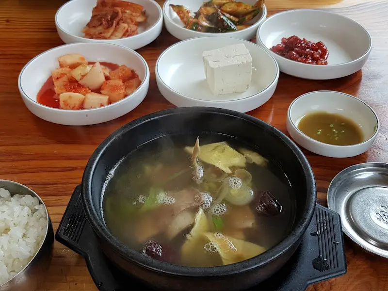 정갈하게 차려진 갈비탕 한 상 차림. 깍두기, 김치 등 다양한 밑반찬과 함께 갈비탕이 뚝배기에 담겨 김을 내뿜고 있다.