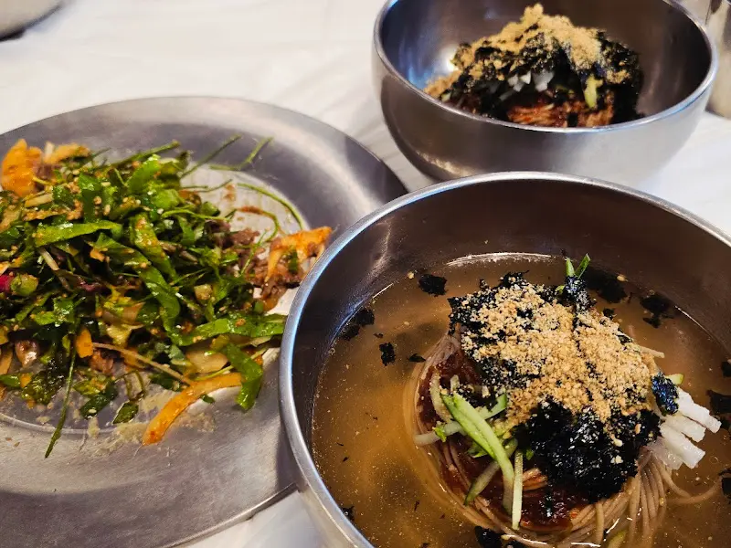 비빔 막국수와 물 막국수, 편육 무침이 함께 놓인 테이블