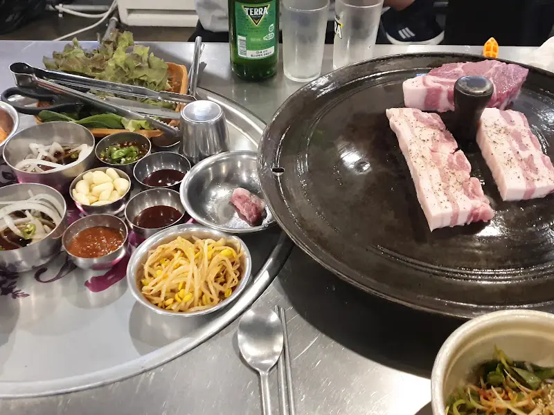 솥뚜껑 위에 올려진 삼겹살과 밑반찬