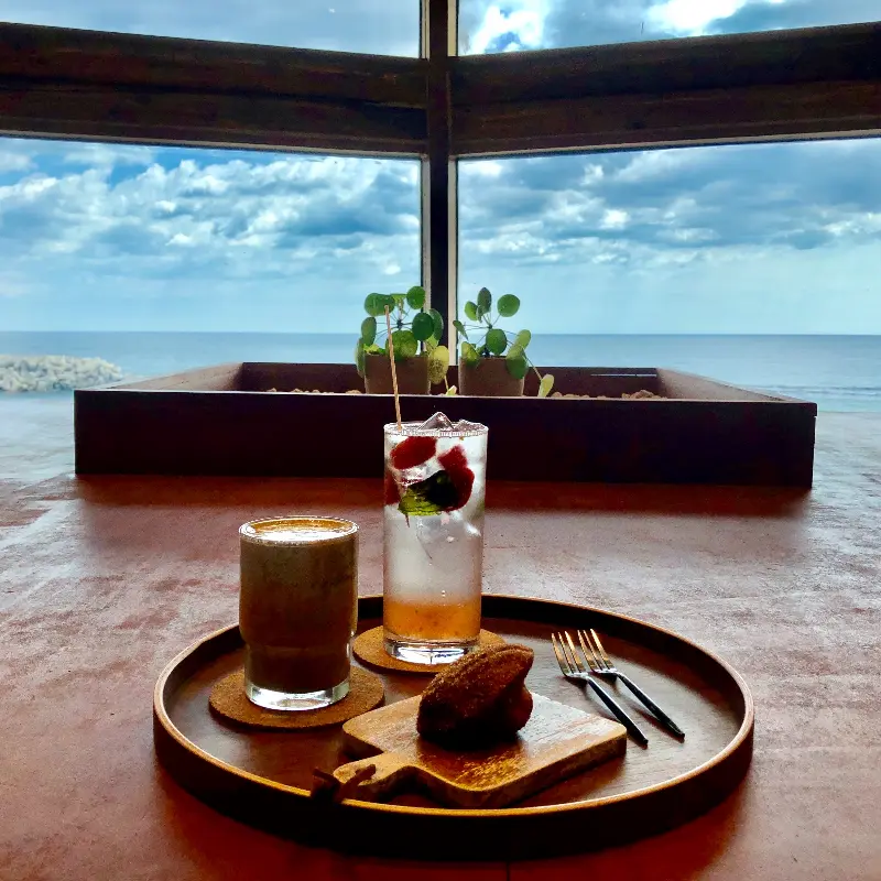 음료와 디저트가 놓인 테이블 너머로 보이는 푸른 바다