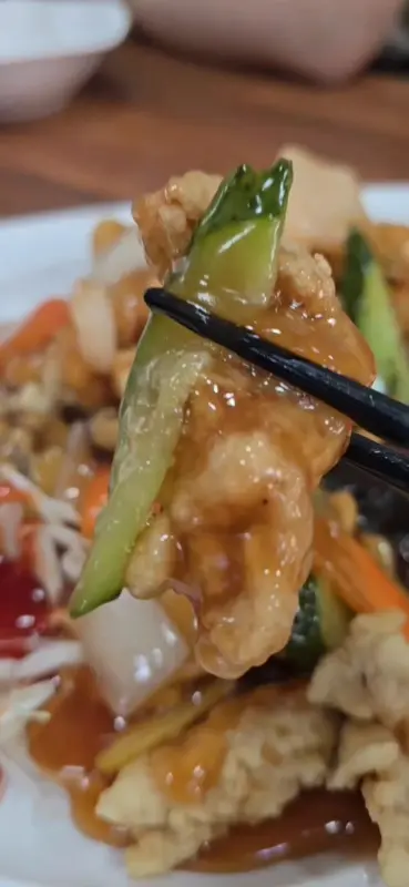 윤기가 흐르는 탕수육을 젓가락으로 집어 올리는 모습