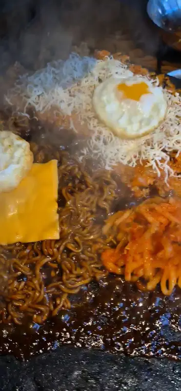 돌판 위에 짜파게티, 김치, 계란후라이가 함께 있는 모습