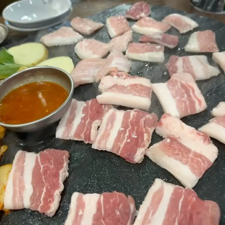 돌판 위에 가지런히 놓인 삼겹살