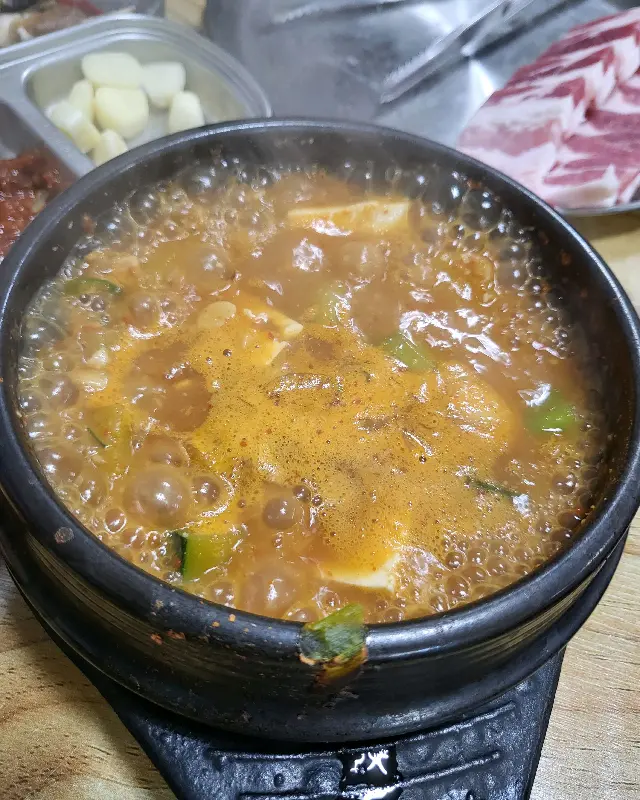 뚝배기 안에서 보글보글 끓고 있는 된장찌개, 두부와 채소가 듬뿍 들어있다.