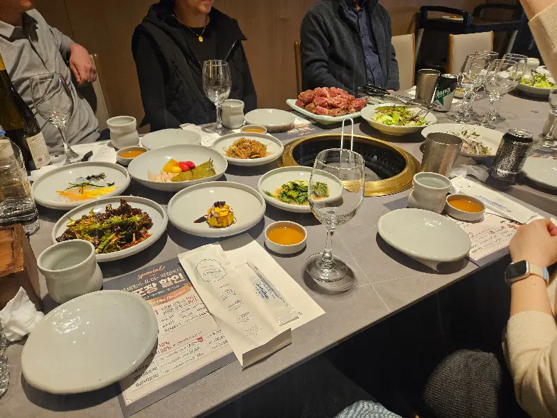 다양한 곁들임 반찬과 고기가 놓여있는 테이블 전경