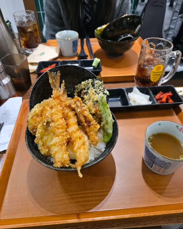 밥 위에 튀김과 소스를 얹어 먹는 모습