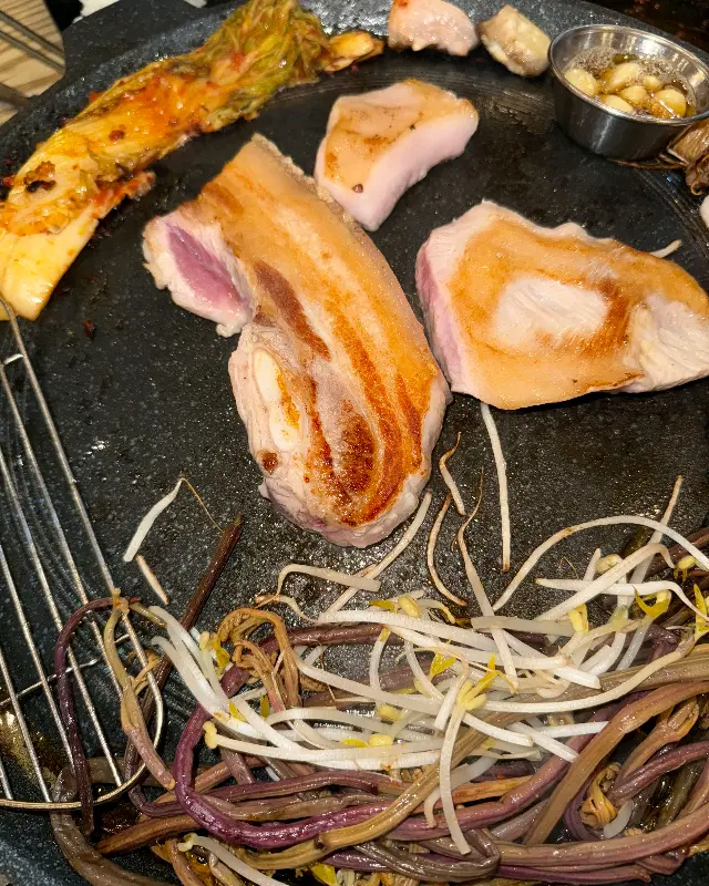 구워진 삼겹살과 김치, 콩나물을 곁들여 먹는 모습