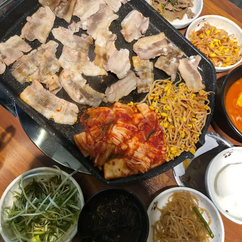 불판 위에서 익어가는 삼겹살과 김치