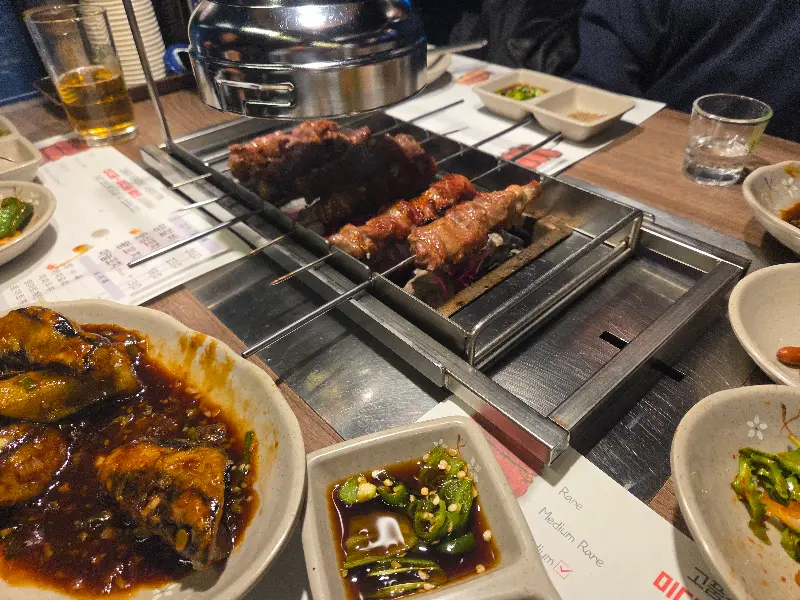 양꼬치, 꿔바로우, 밑반찬이 놓인 테이블 전경