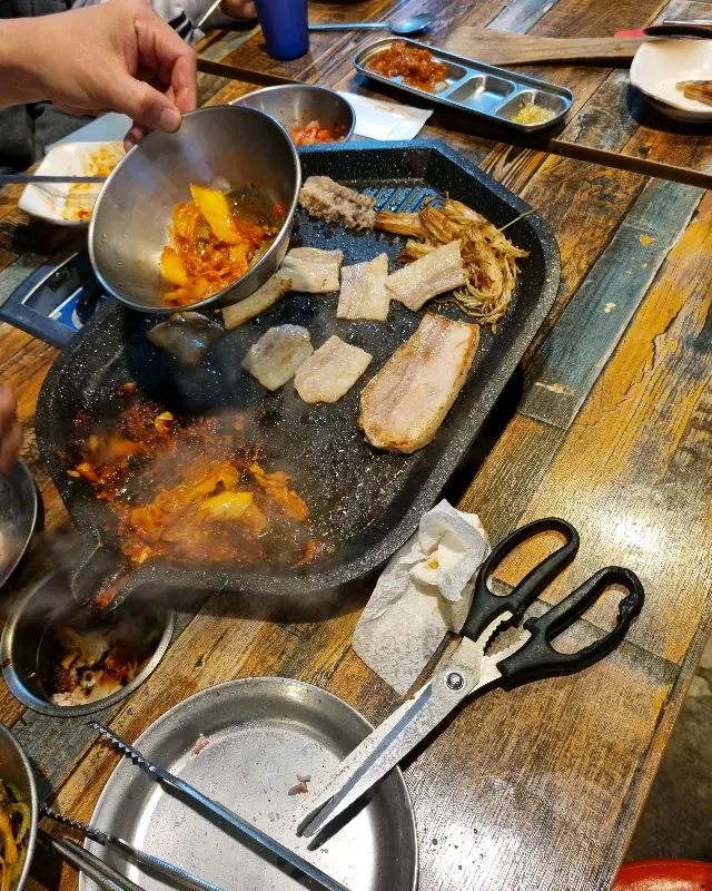 불판 위에서 익어가는 고기와 김치, 그리고 된장찌개