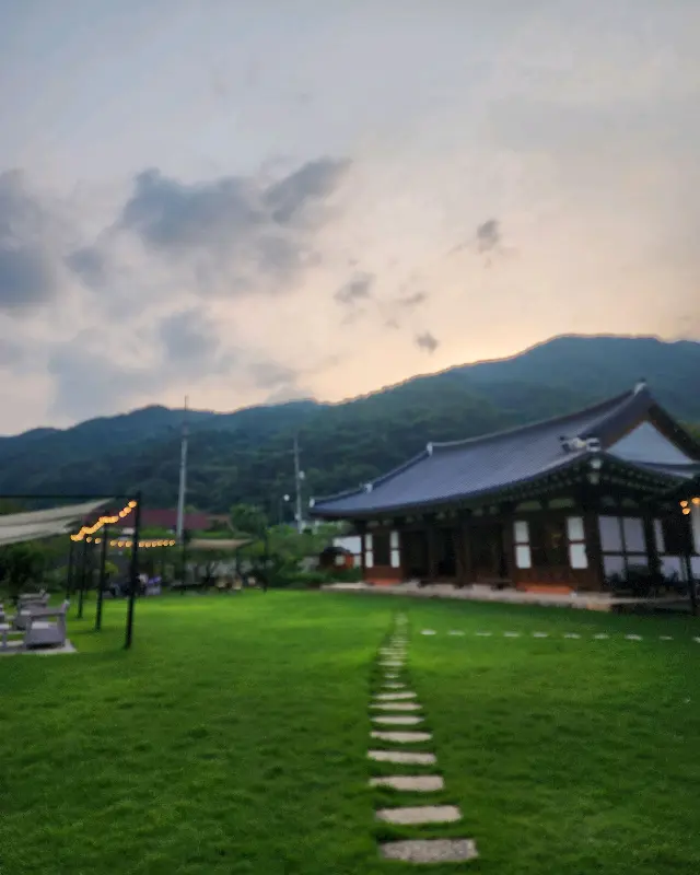 푸른 잔디밭과 한옥 건물이 조화롭게 어우러진 카페 소나무의 전경