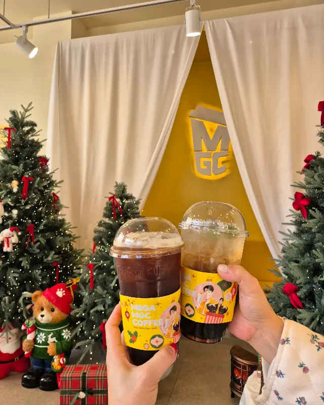 크리스마스 트리 앞에서 커피를 들고 있는 모습