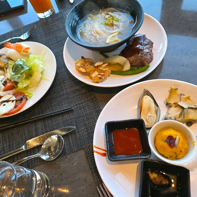 스테이크, 샐러드, 전복 등 다양한 음식이 담긴 접시