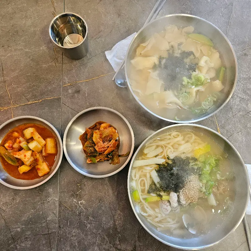 수제비와 칼국수, 김치, 깍두기가 놓인 테이블 전경