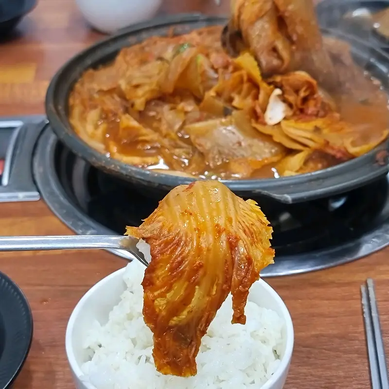 잘 익은 묵은지 한 조각을 밥 위에 올려 먹음직스럽게 담아낸 모습