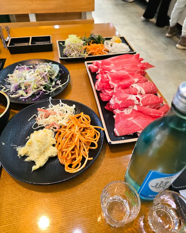 테이블 위에 놓인 샤브샤브 재료와 샐러드바 음식들