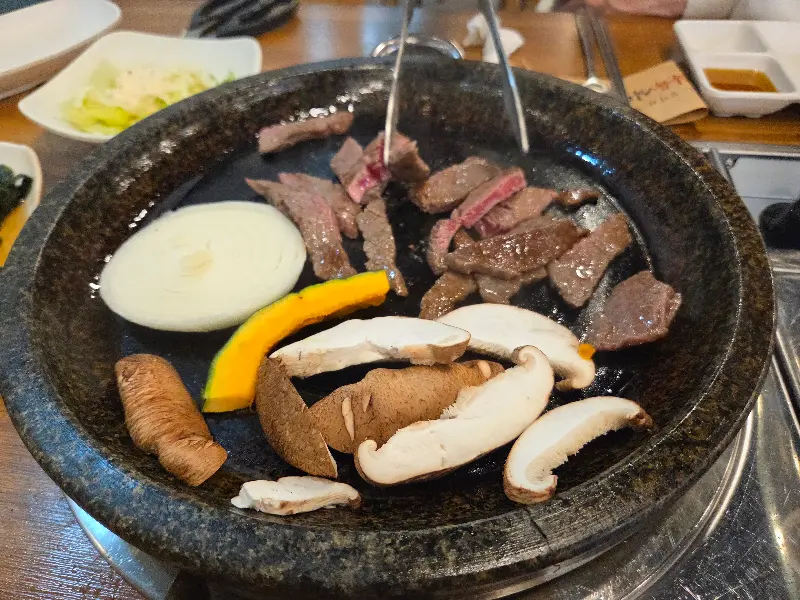 돌판 위에서 익어가는 소고기, 버섯, 양파