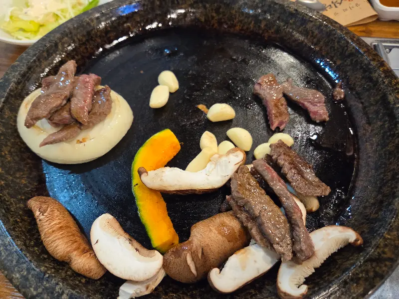 돌판 위에 구워진 소고기, 버섯, 양파