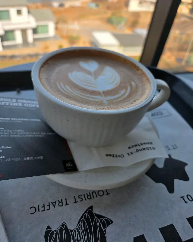 창밖의 바다를 배경으로 놓인 카페 라떼
