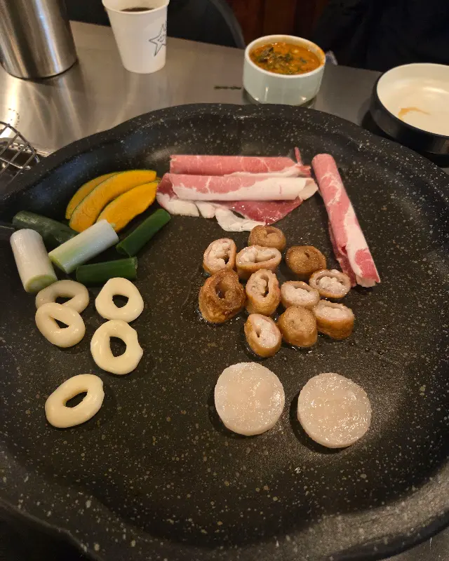 돌판 위에 막창, 차돌박이, 관자가 함께 구워지는 모습