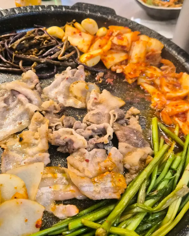 노릇노릇하게 구워진 냉동 삼겹살과 김치를 함께 먹는 모습