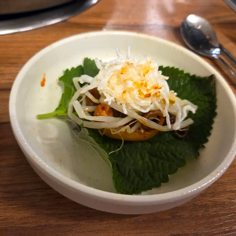 깻잎 위에 쭈꾸미와 천사채를 올려 쌈을 싼 모습