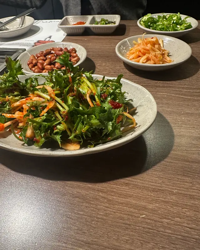 테이블 위에 놓인 샐러드, 땅콩, 고추 등 밑반찬 클로즈업 샷