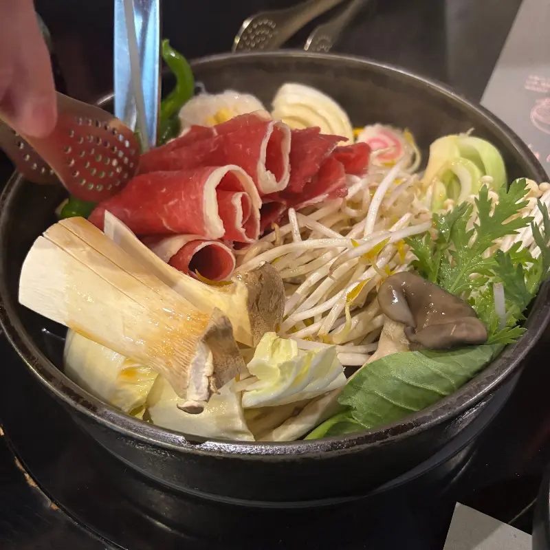 스키야키에 고기와 야채를 넣는 모습