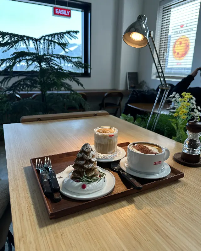 테이블 위에 놓인 음료와 디저트, 창밖 설산 뷰