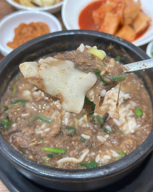 수저로 고사리 해장국을 뜨는 모습. 메밀 조베기가 함께 떠올려져 보인다.