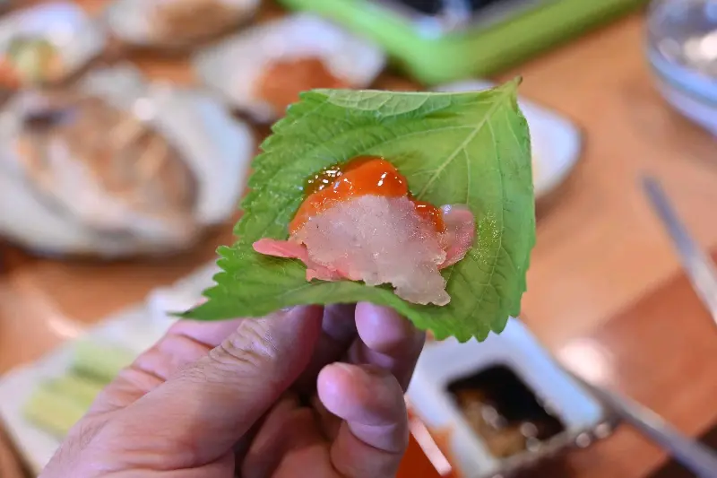 깻잎 위에 회 한 점과 양념을 올려 쌈을 만든 모습