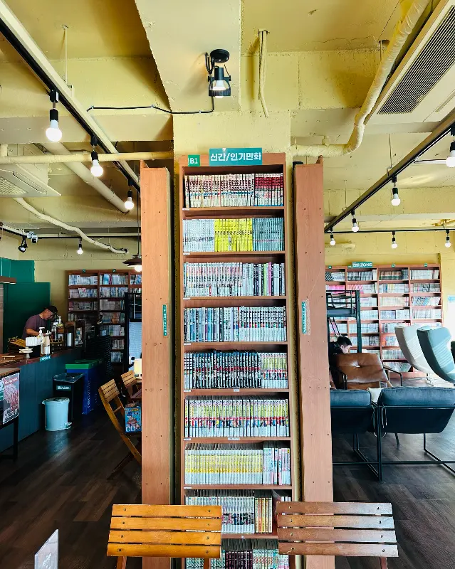 만화책이 가득한 책장과 아늑한 분위기의 인테리어가 인상적이다.