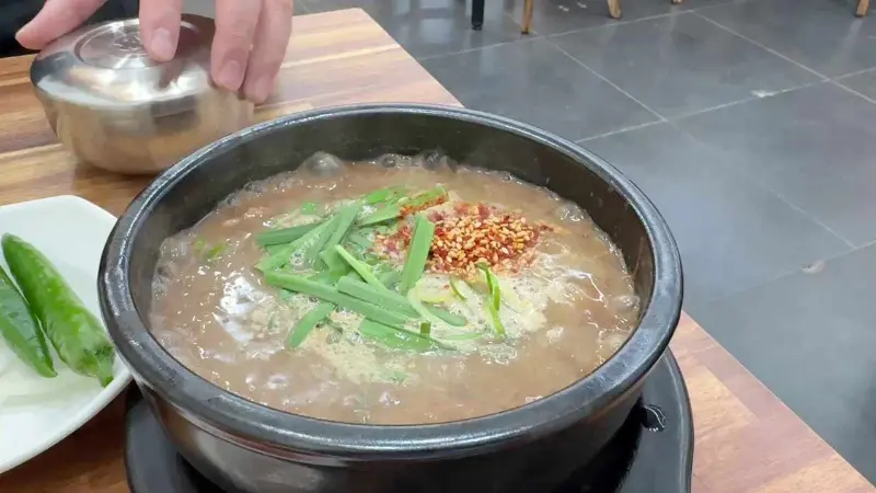 뚝배기에 담긴 고사리 육개장. 파와 고춧가루가 고명으로 올려져 있다.