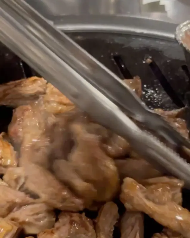 잘 구워진 고기를 집게로 집는 모습